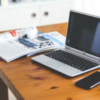 laptop on wooden table with notepad