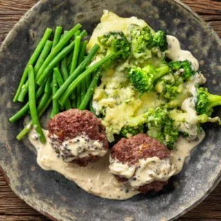 bunless beef burger on a plate with green beans
