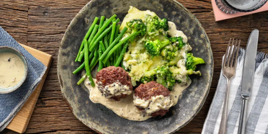bunless beef burger on a plate with green beans