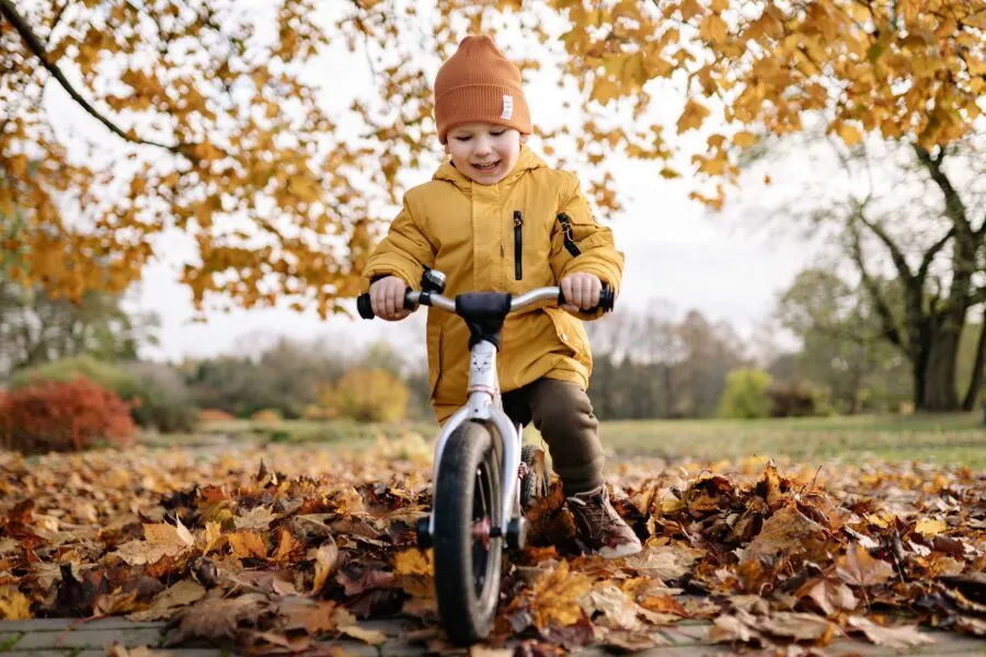 Child in yellow jacket on balance bike