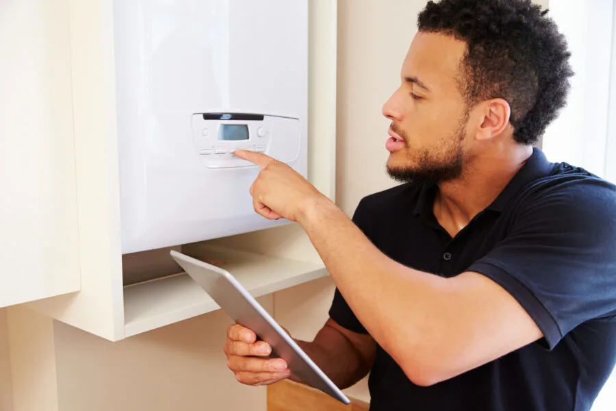 Technician servicing boiler holding tablet computer
